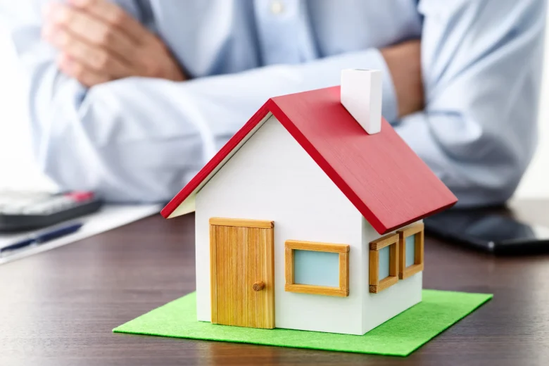 腕を組む男性と一軒家