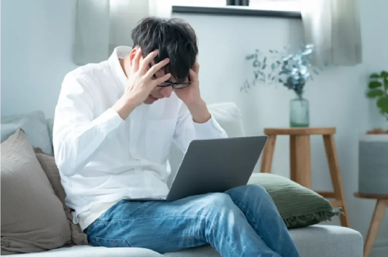 パソコンを見つめ頭を抱える人