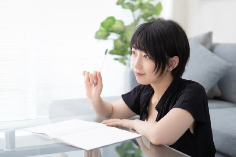 紙とペンを持ち微笑む女性